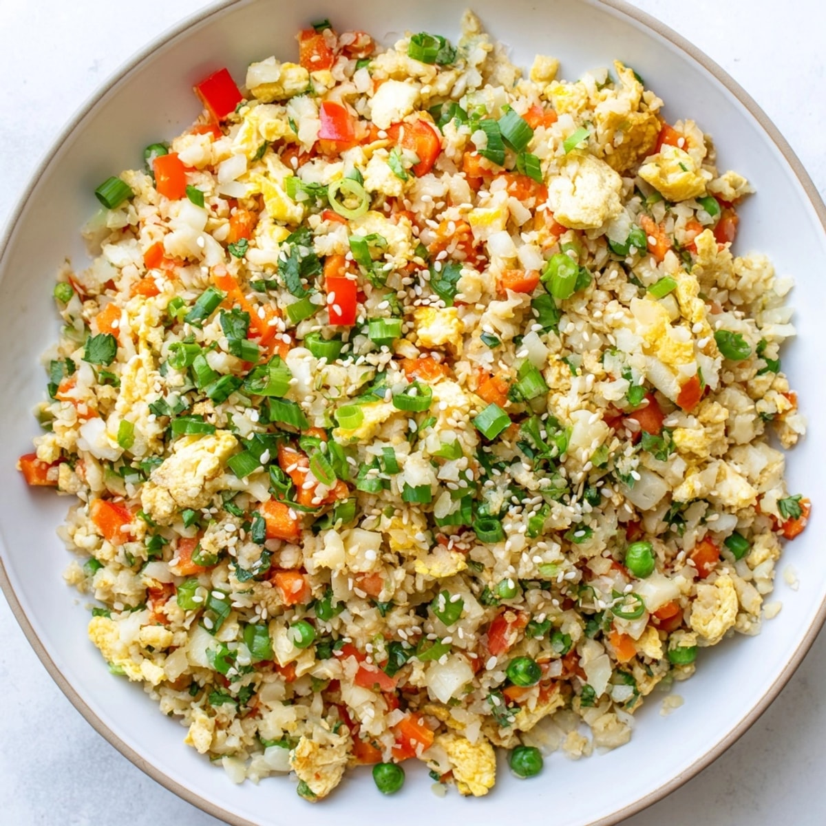 Close-up of Cauliflower Fried Rice: Steaming grains, colorful vegetables, savory sauce glistening.