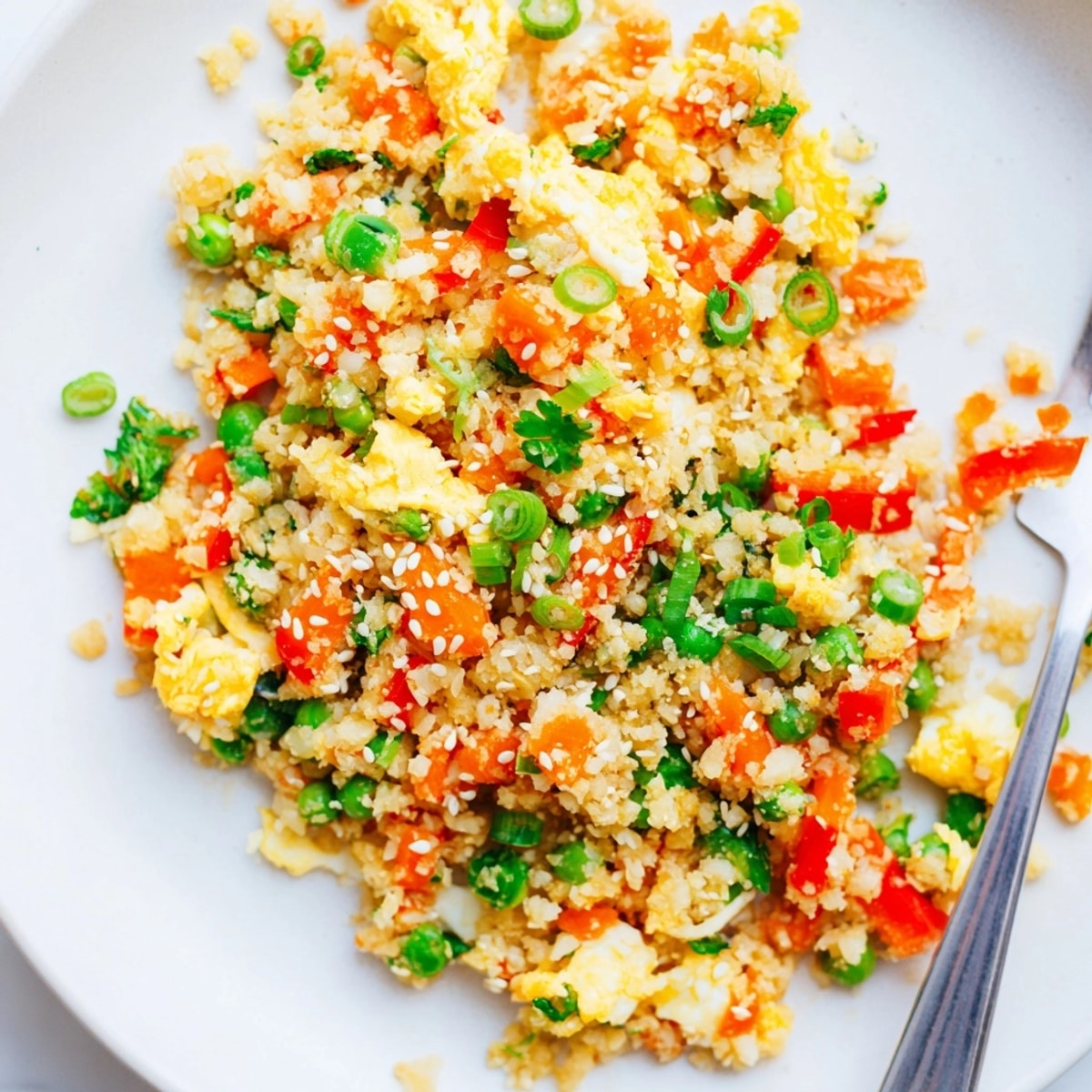 Scoop of healthy Cauliflower Fried Rice, capturing textures of soft cauliflower and crisp peppers.