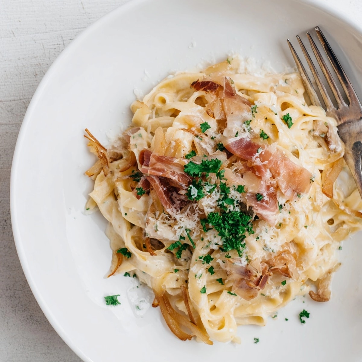 French Onion Pasta featuring crispy prosciutto: A rich bowl with grated Gruy&egrave;re cheese.
