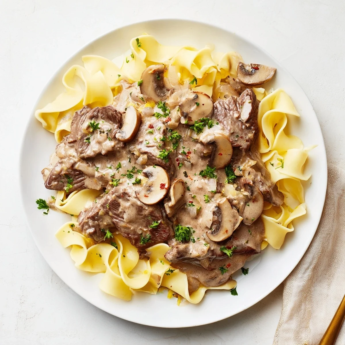 Tender beef stroganoff with egg noodles, drenched in a creamy sauce, perfect comfort food.