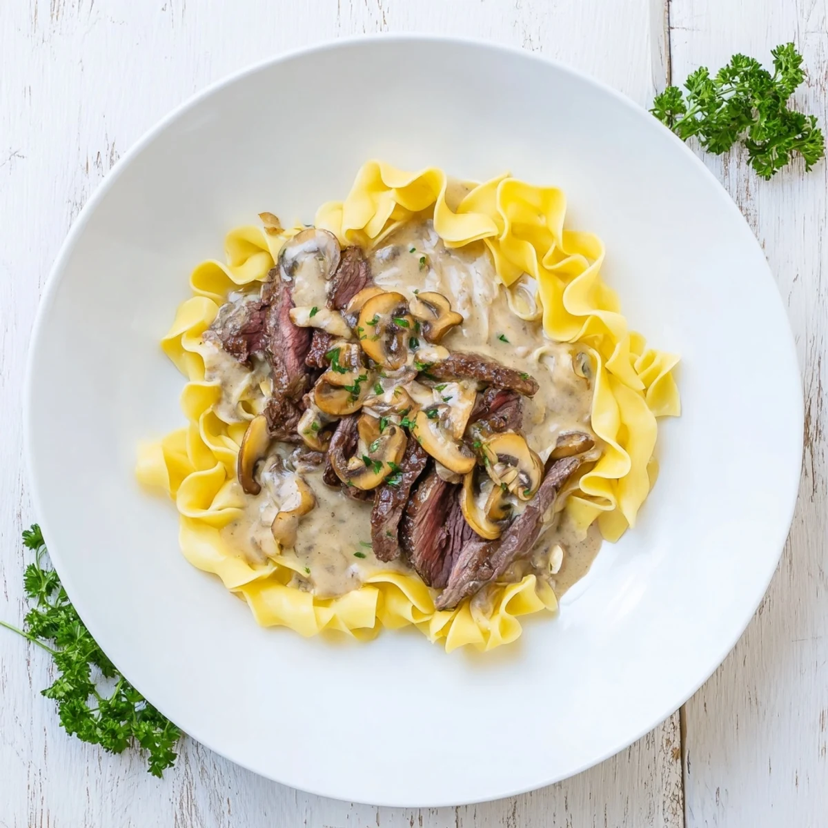 A close-up of savory beef stroganoff, featuring rich sauce atop fluffy egg noodles, ready to eat.