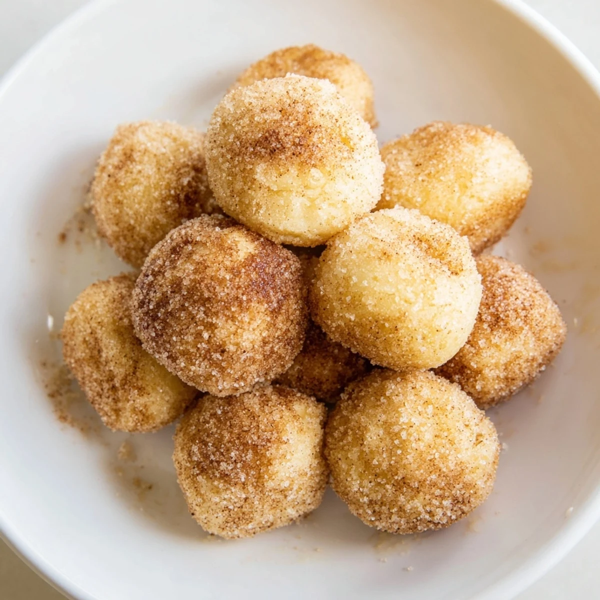 Golden-brown Cinnamon Sugar Donut Holes, freshly fried and coated in sweet cinnamon sugar, ready to eat.