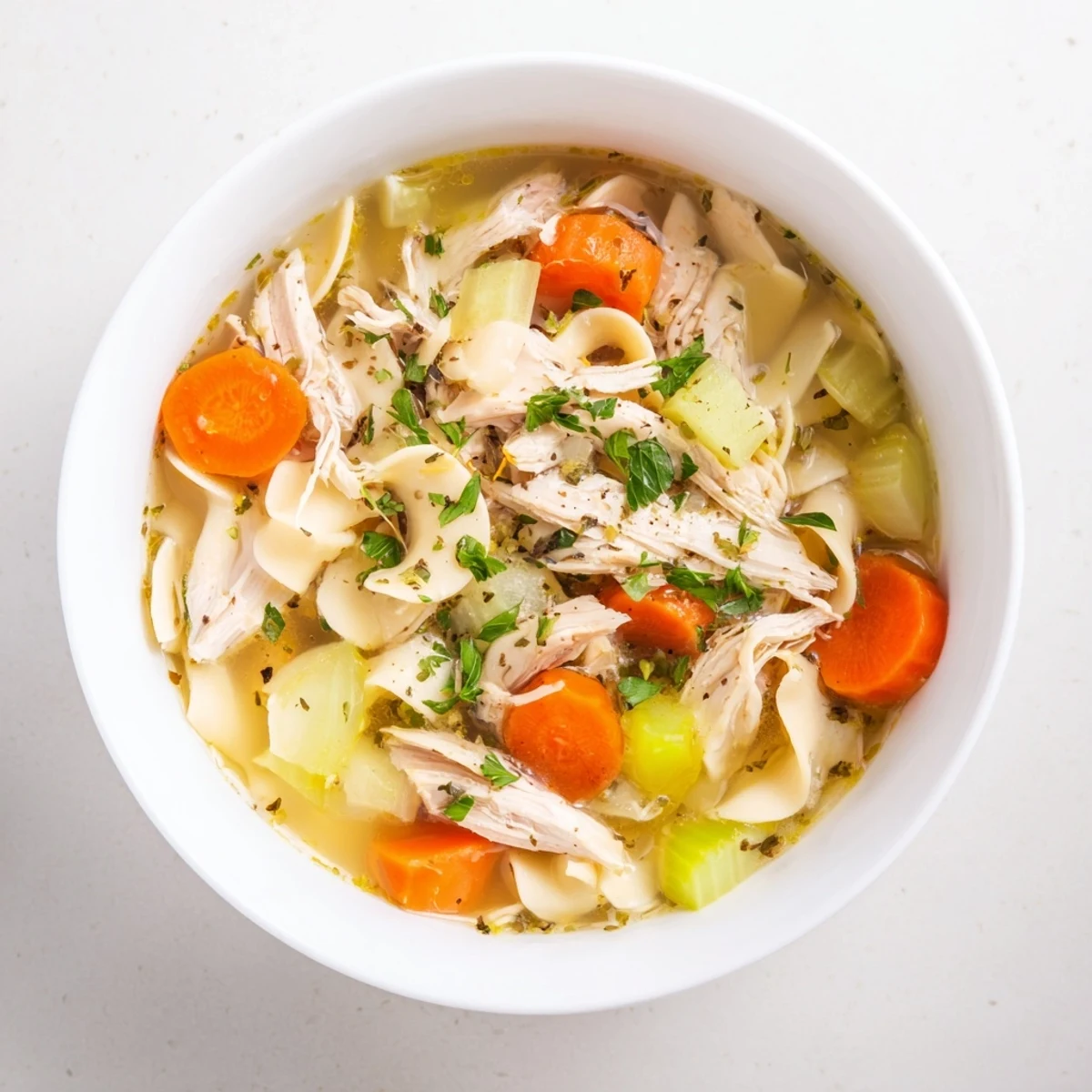 Steaming bowl of homemade Chicken Noodle Soup; chicken and noodles visible in savory broth.