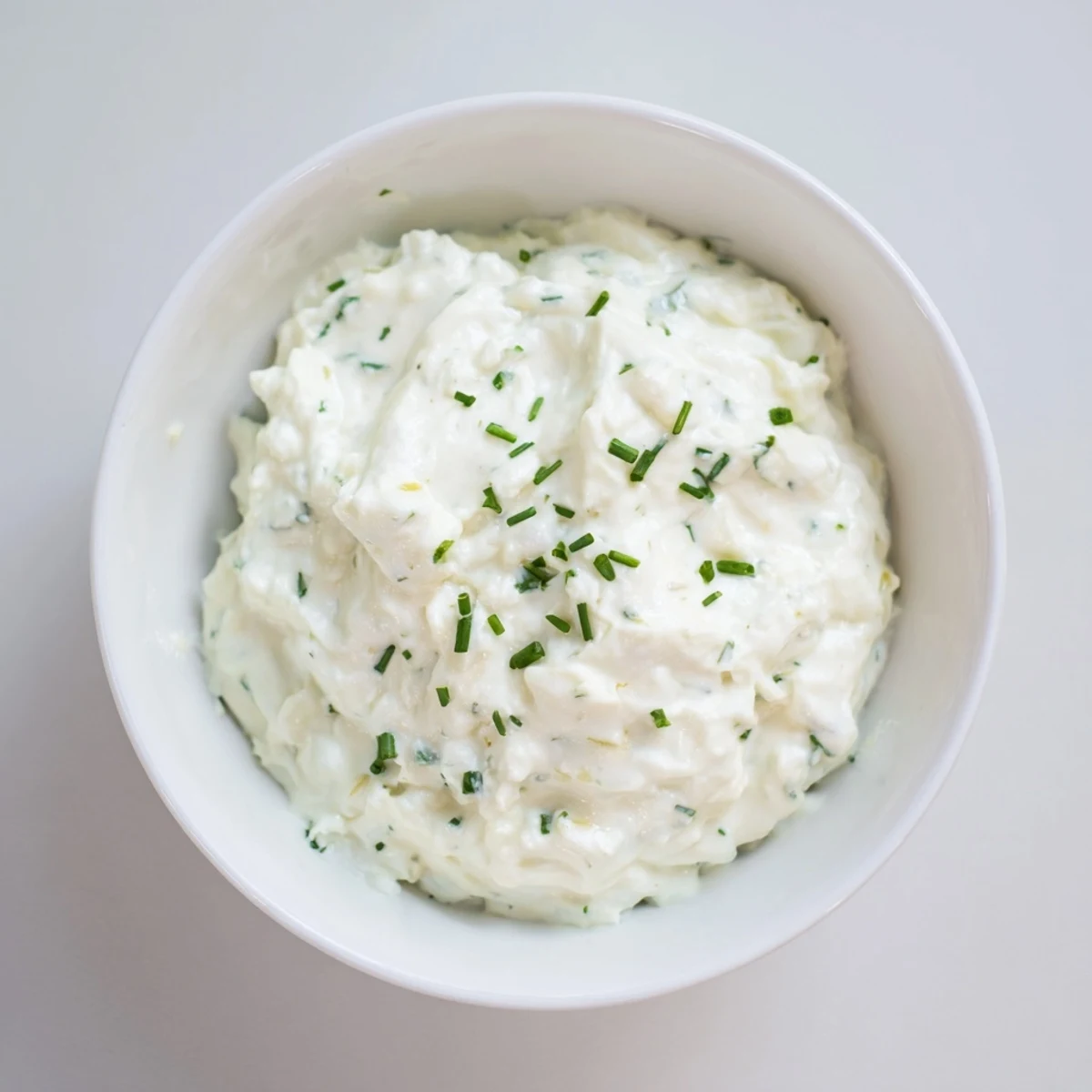 A bowl of creamy garlic dip, ready to serve with colorful fresh vegetable sticks.