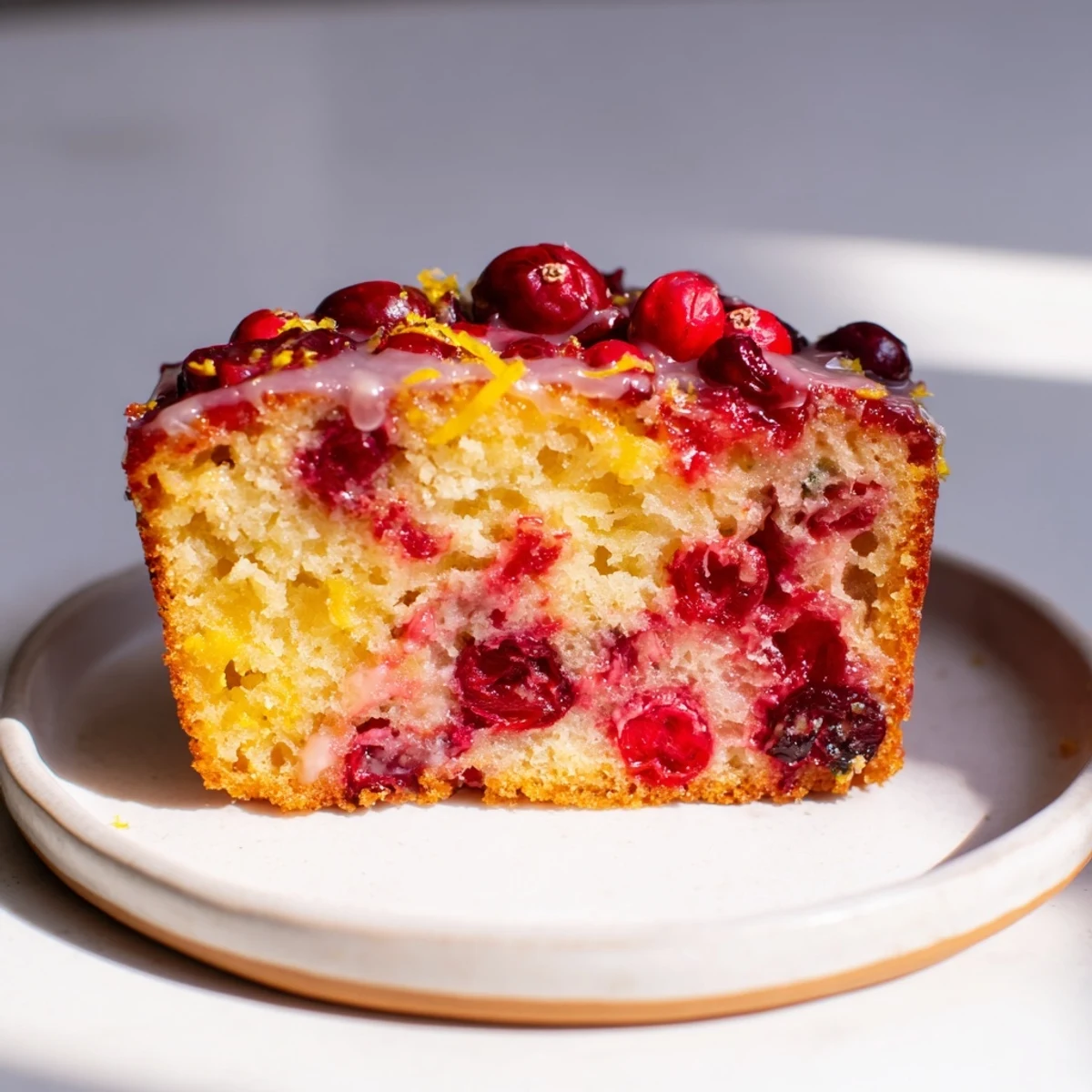 This golden Cranberry Orange Loaf Cake, sliced and ready to serve, is bursting with bright flavors.