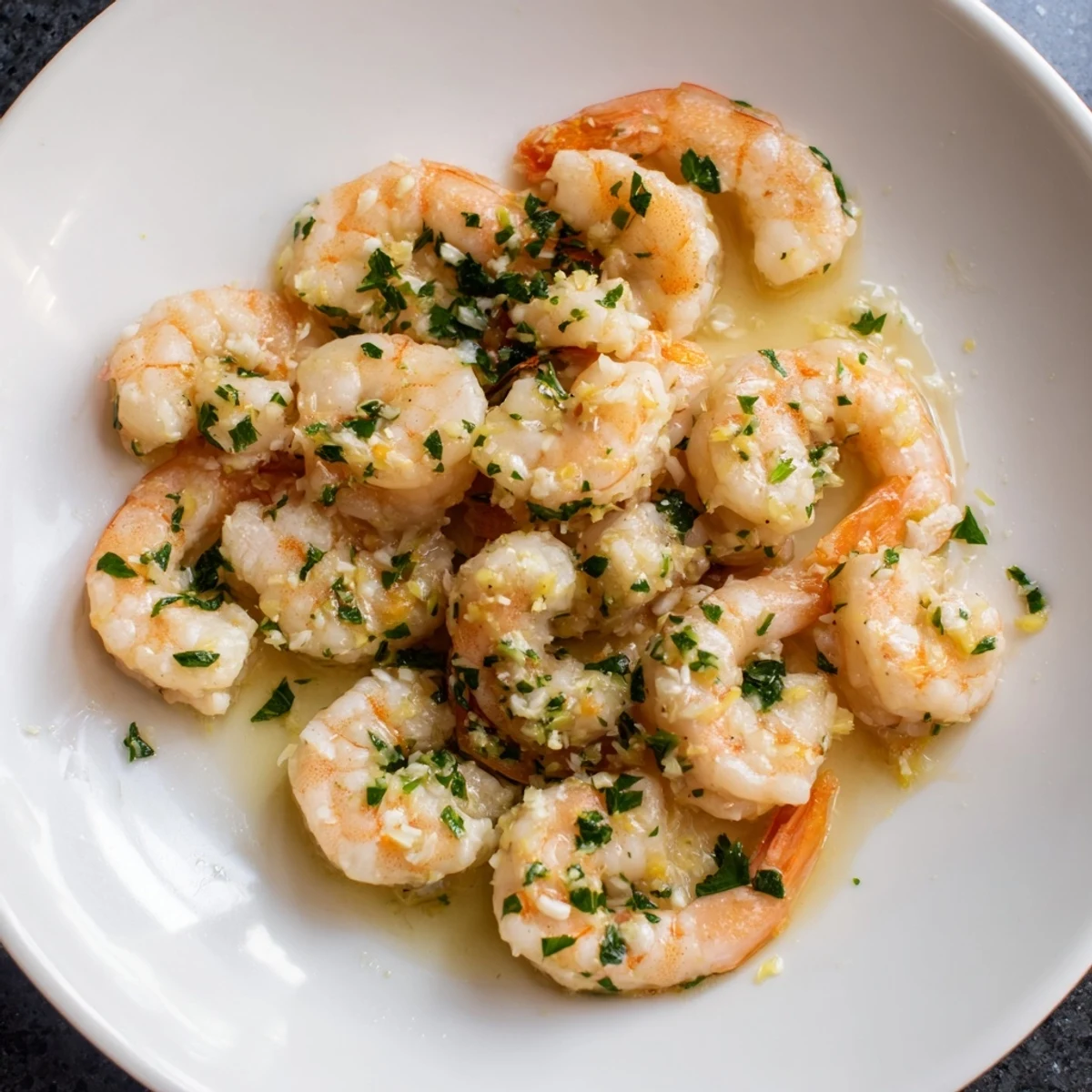 Golden garlic shrimp glistening in a buttery sauce, ready to serve with lemon wedges near.