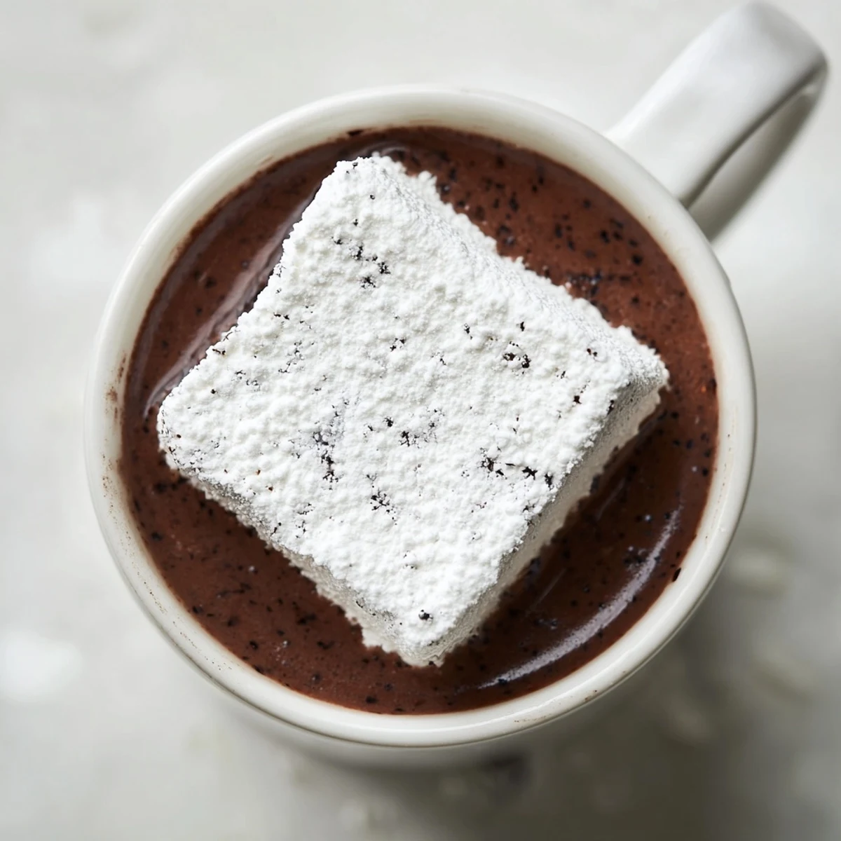 Homemade Fluffy Vanilla Bean Marshmallow Floaters dusted with powdered sugar, melting into creamy hot cocoa.