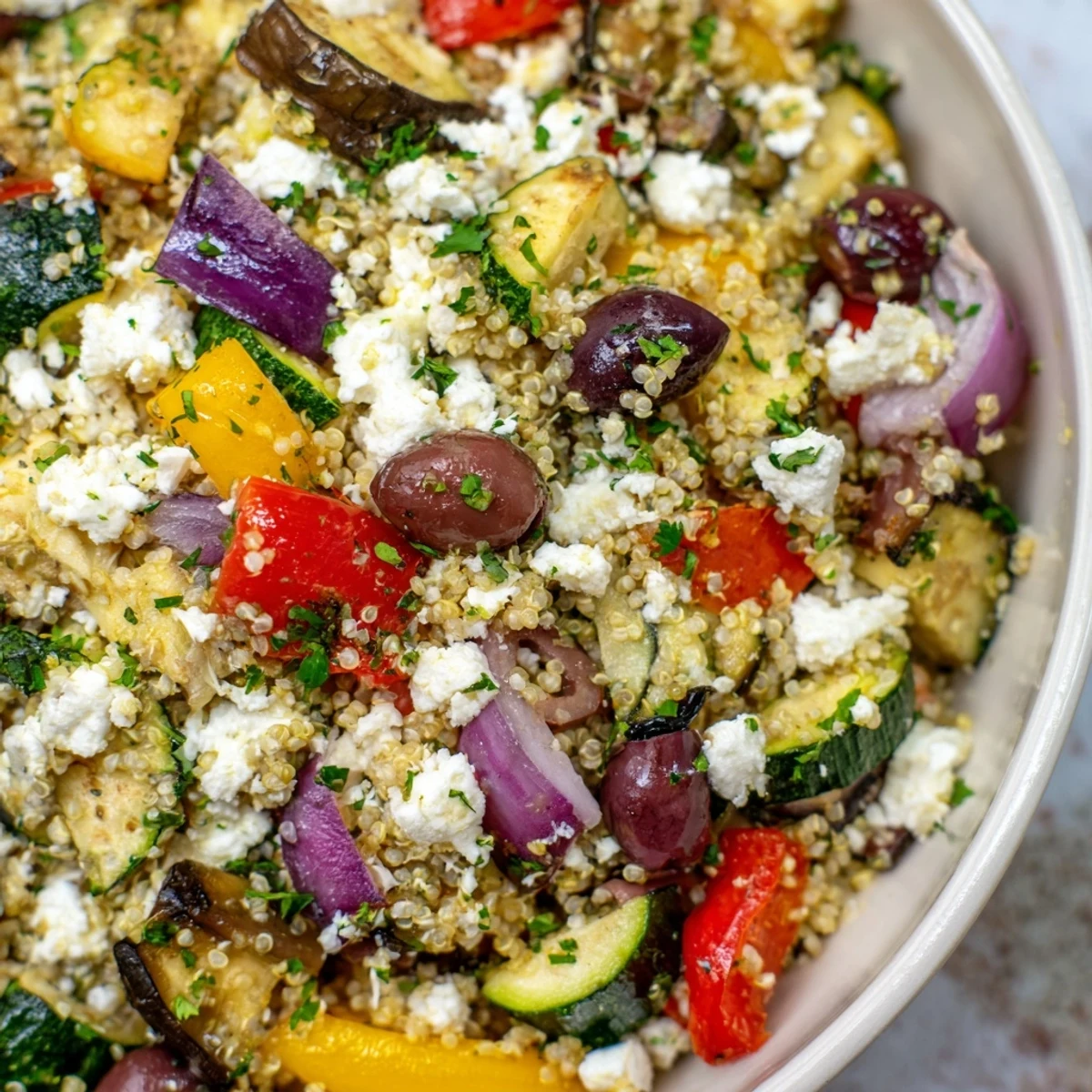 Freshly roasted zucchini, bell peppers, and eggplant rest atop fluffy quinoa in this Mediterranean Quinoa Salad, finished with a lemon-herb dressing.