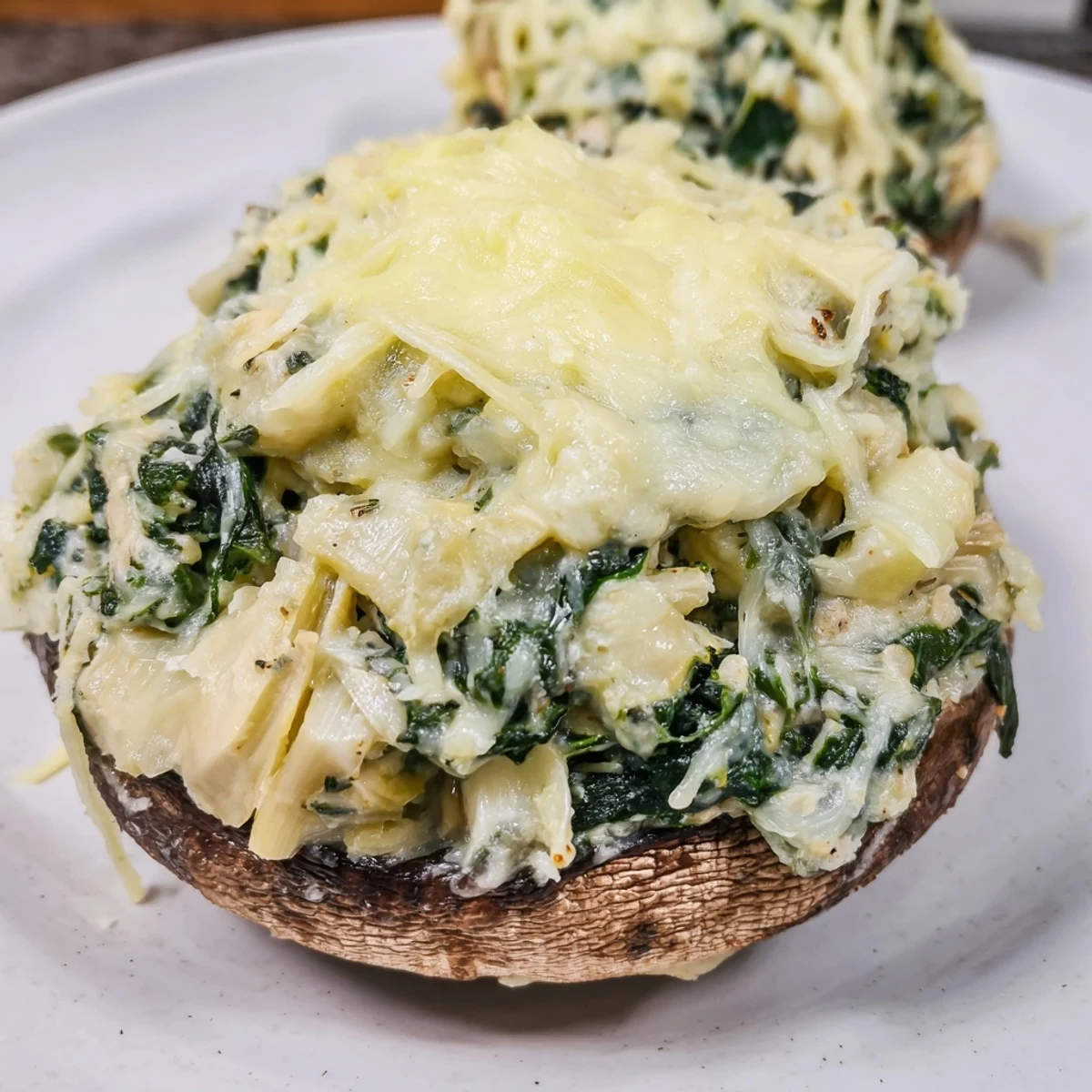 Savory Cheesy Spinach and Artichoke Stuffed Portobello Mushrooms garnished with fresh parsley for an appetizer.