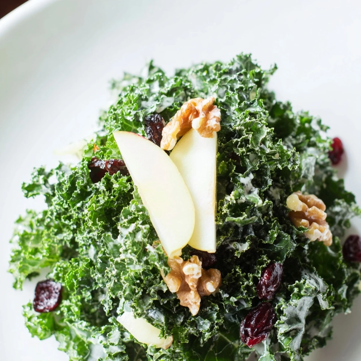 Overhead view of Winter Kale Salad with Apple and Sharp Cheddar, showcasing crisp apples, sharp cheddar cubes, and pumpkin seeds over massaged kale.