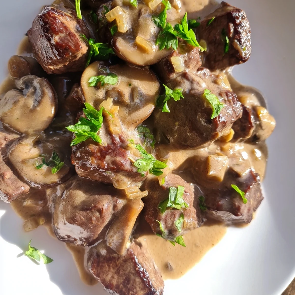 Sizzling steak bites coated in garlic butter and creamy mushroom sauce, ready to be served with crusty bread.