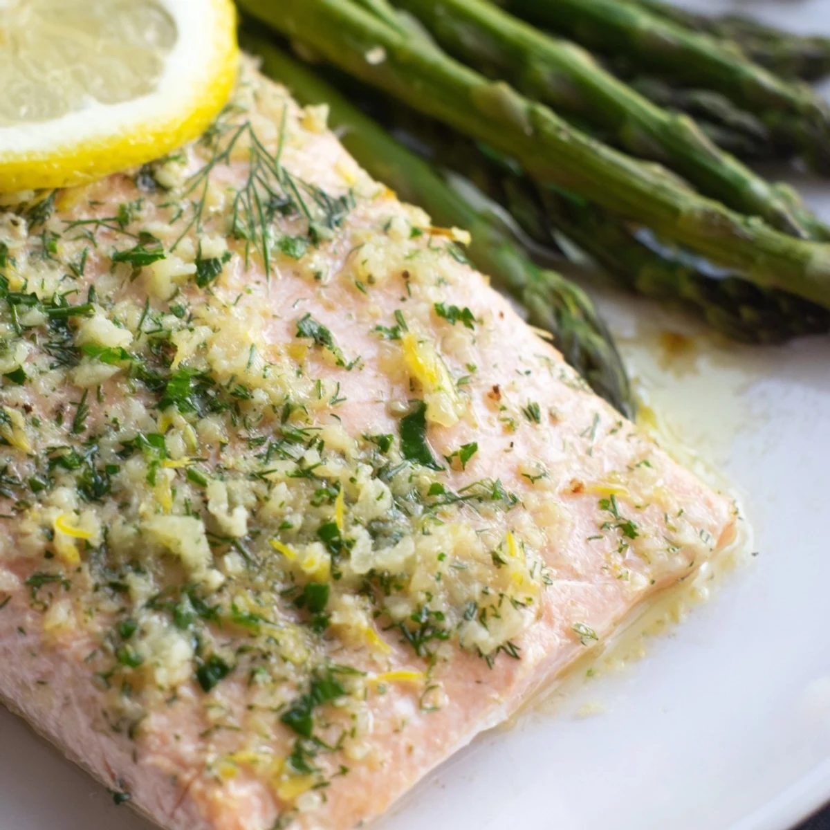 Baked Lemon Garlic Butter Salmon fillets and roasted asparagus garnished with fresh parsley on a baking sheet.