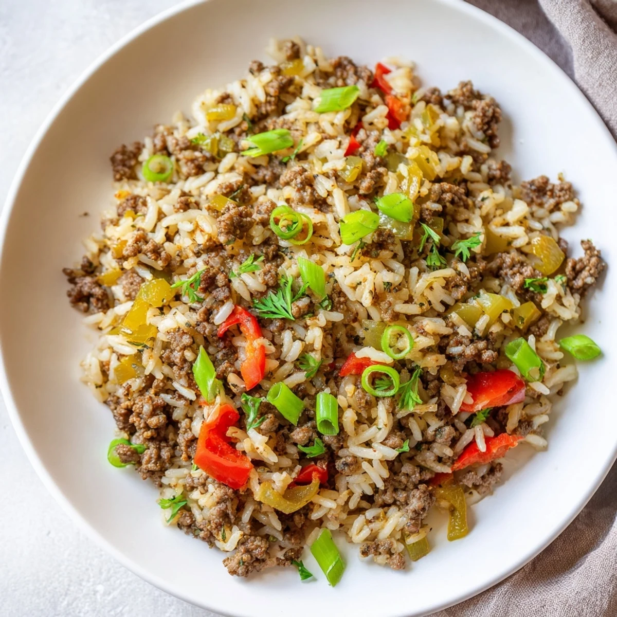 Spicy Cajun Dirty Rice with Ground Beef and Peppers in a white bowl, perfect for a Southern dinner.