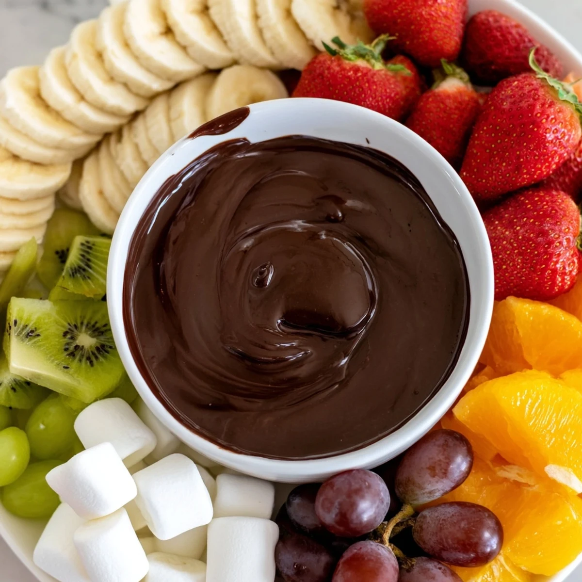Golden melted chocolate fondue with marshmallows and fresh sliced strawberries and bananas for dipping.  