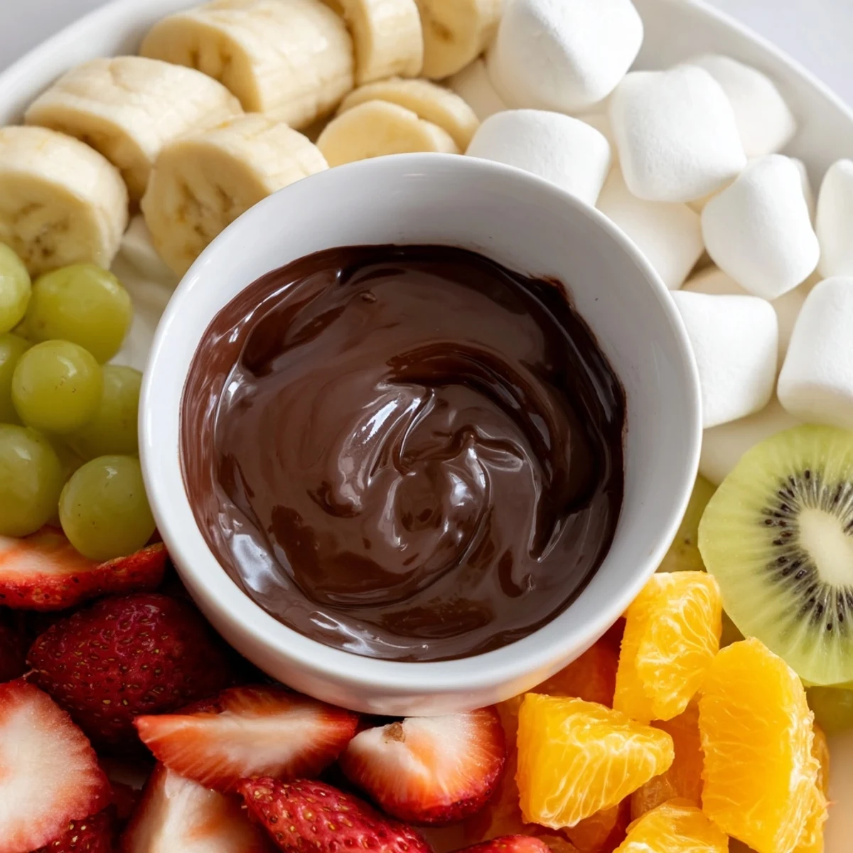 Decadent chocolate fondue with marshmallows and fruit on a platter, perfect for sharing.