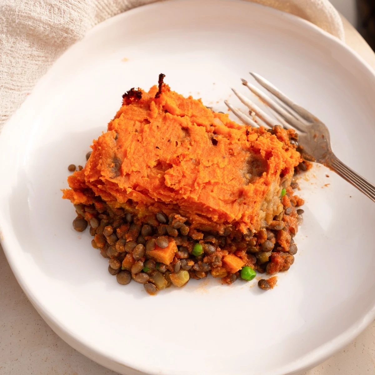 Golden-brown mashed sweet potatoes topping a hearty Vegan Lentil and Sweet Potato Shepherds Pie, served in a rustic baking dish.
