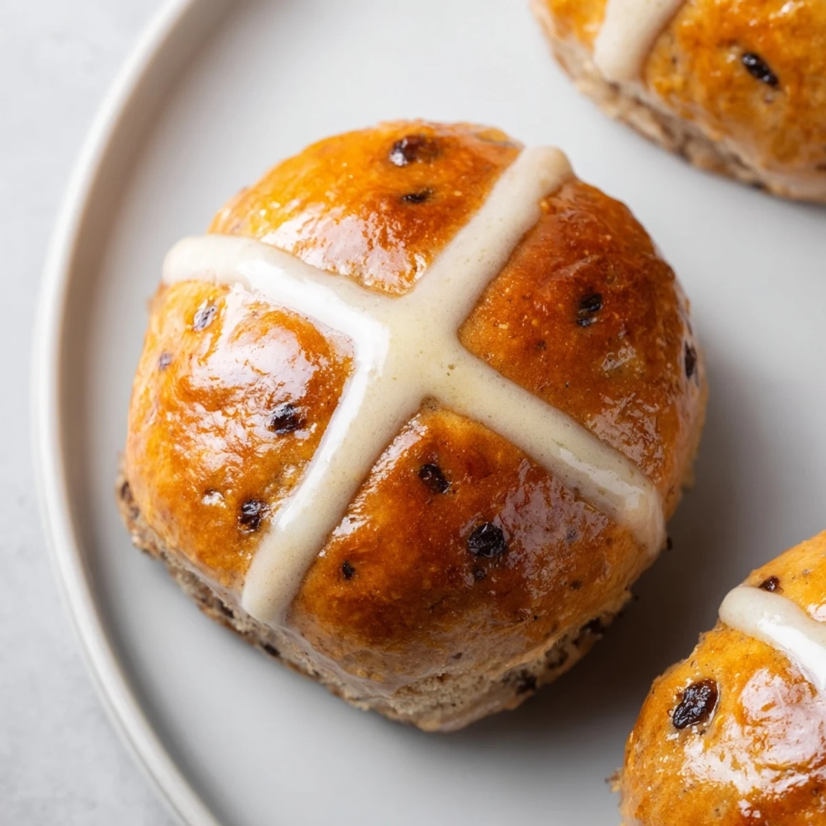 Freshly baked Hot Cross Buns with Currants and Spices dusted with flour on a wooden board.