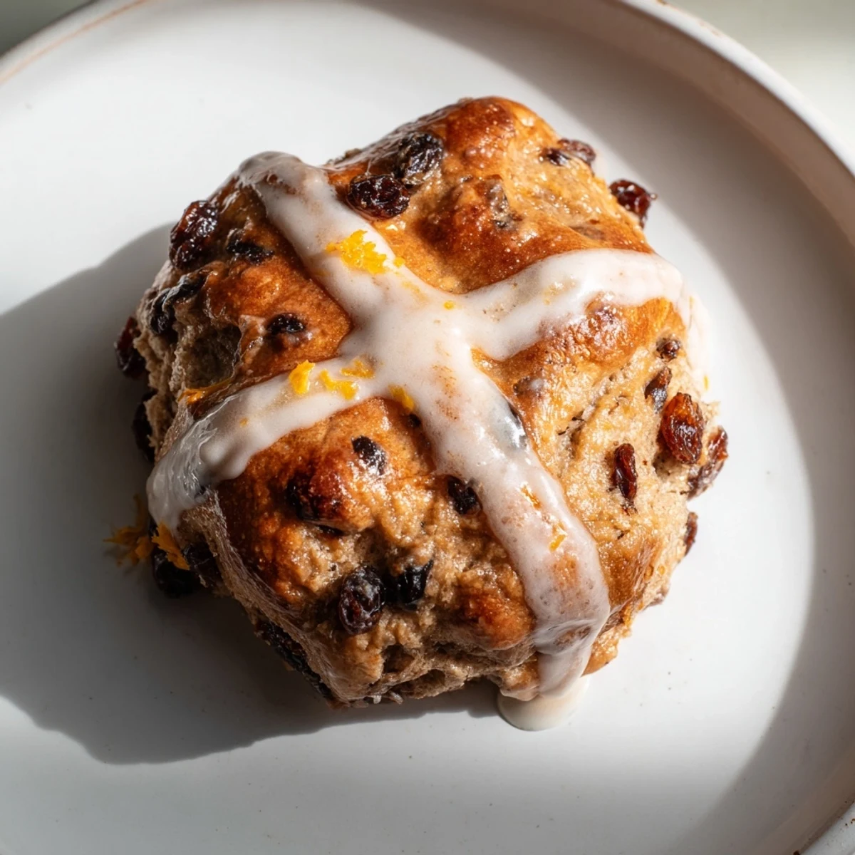 Freshly baked Hot Cross Buns with Raisins and Orange Glaze glazed and cooling on a wire rack.  