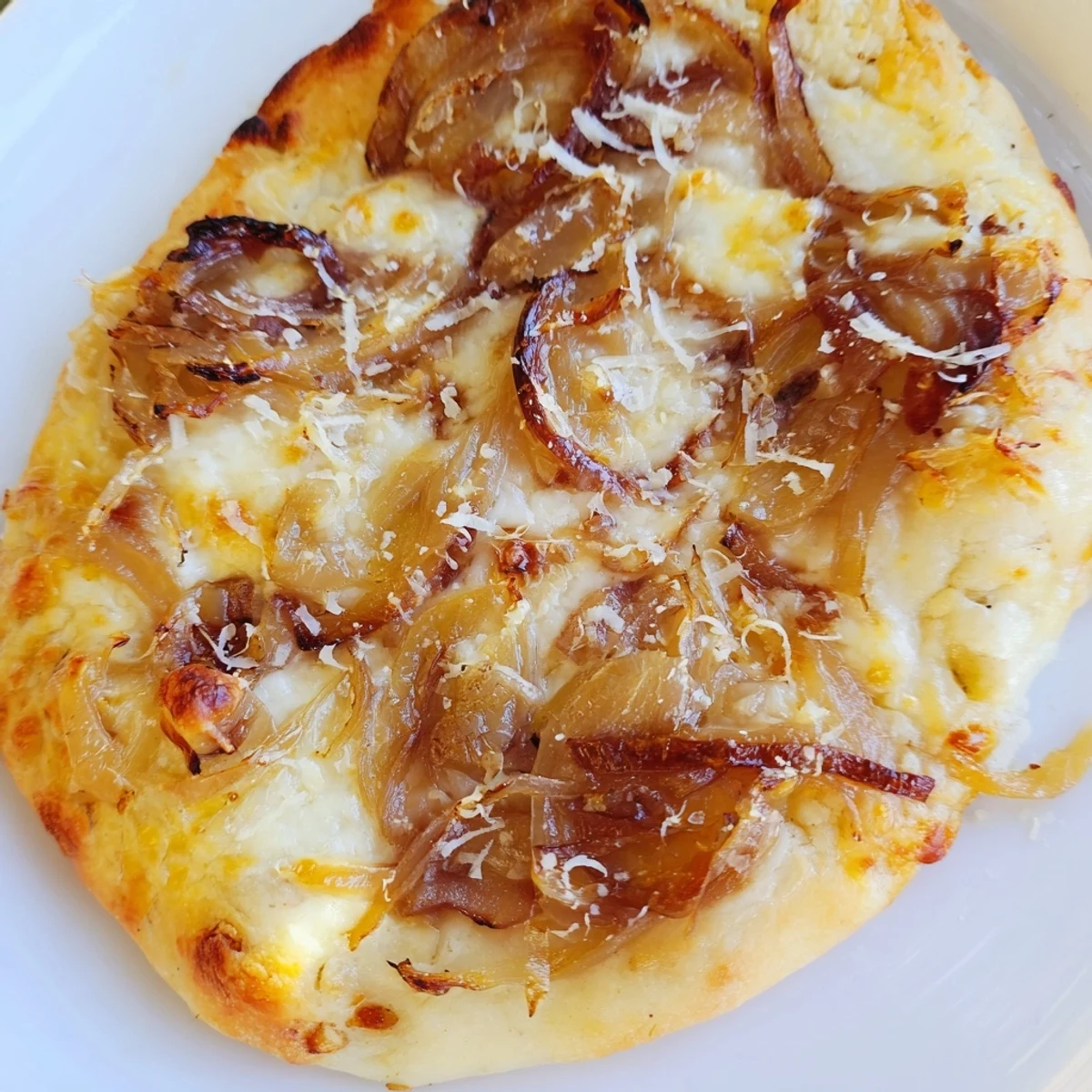 A close-up of Caramelized Onion Pizza With Melty Cheese, golden crust bubbling with gooey cheese and sweet onions.