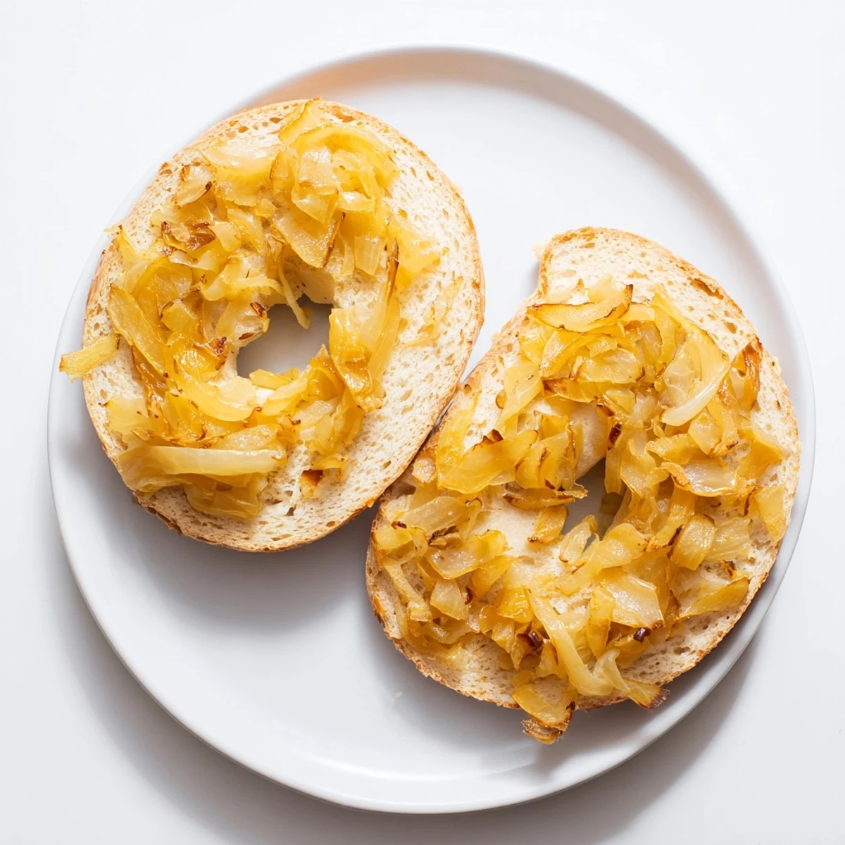 Golden-brown Sourdough Onion Bagels fresh from the oven, topped with deeply caramelized onions on a rustic wooden board.