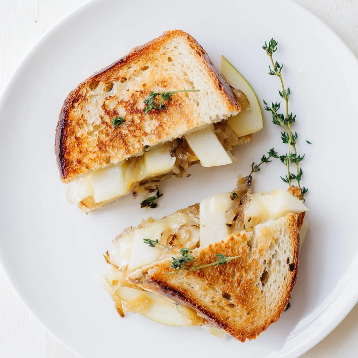 Serving suggestion for Pear, Apple & Grilled Cheese with Caramelized Onions showing crisp bread halves revealing layers of gooey cheddar and tender fruit.