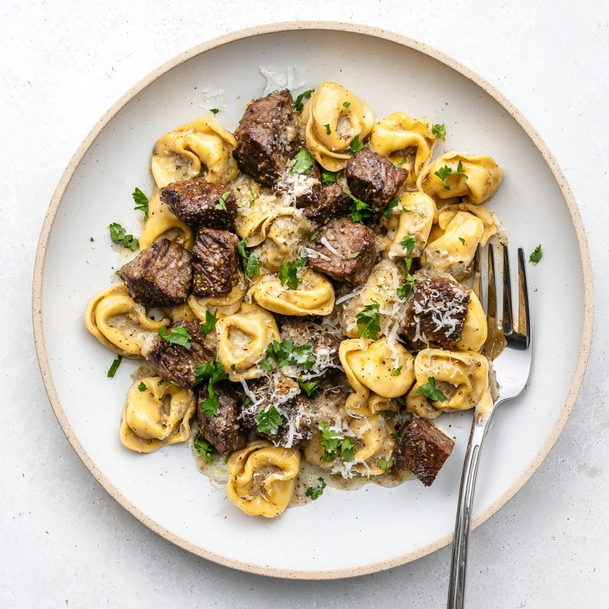 Garlic Steak Tortellini plated with a generous sprinkle of Parmesan and fresh parsley, ready to enjoy immediately.