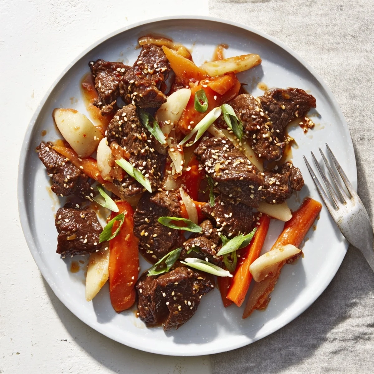 Savory-sweet Korean Style Pot Roast with sesame seeds and scallions over soft beef and vegetables, perfect alongside kimchi.