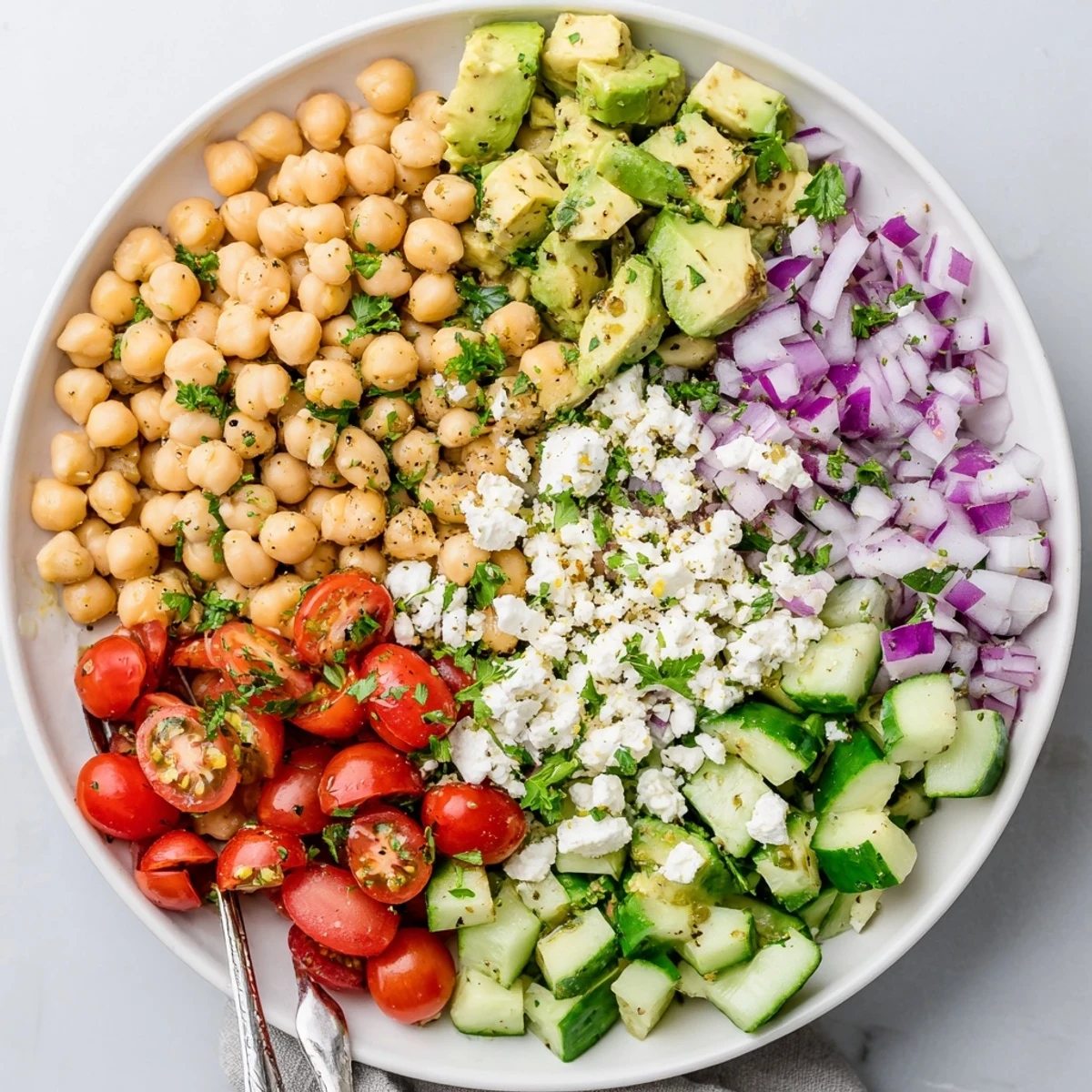 Close-up of a colorful Chickpea Feta Avocado Salad, showcasing green avocado, red tomatoes, white feta, and chickpeas tossed with fresh parsley.