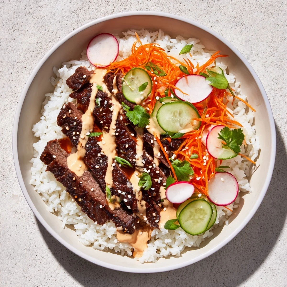 Garnished with cucumber and radish slices, this Irresistibly Easy Korean BBQ Steak Rice Bowls with Spicy Cream Sauce looks vibrant.