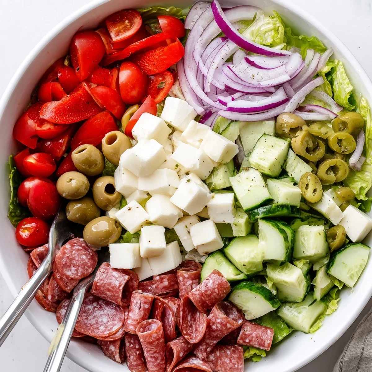 Colorful Italian chopped salad with fresh vegetables, salami, and homemade zesty dressing served in a white bowl