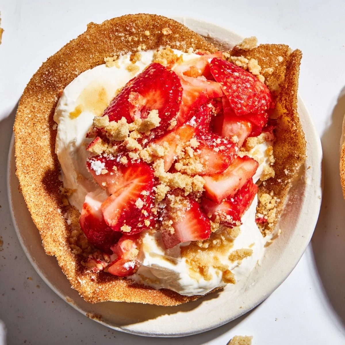 Golden brown cinnamon sugar taco shell stuffed with creamy strawberry crunch cheesecake filling and fresh diced berries