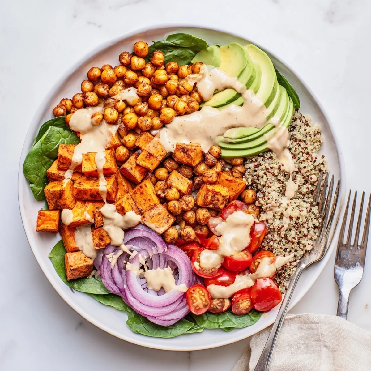 Vibrant hearty sweet potato bowl arranged with spinach, chickpeas, and cherry tomatoes in a colorful layered presentation