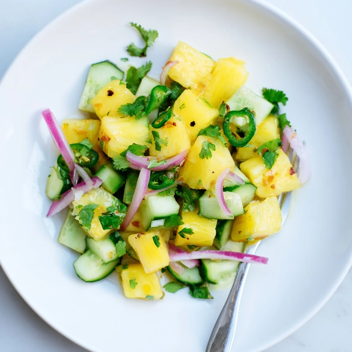 Fresh pineapple cucumber salad tossed in zesty lime vinaigrette with colorful red onion and cilantro