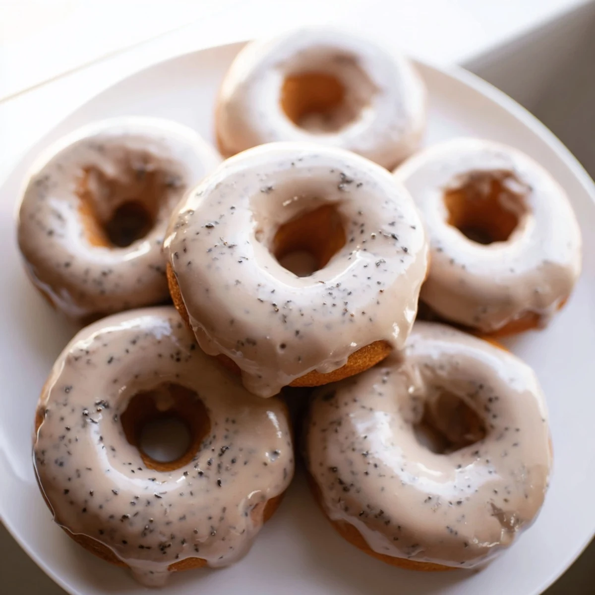 Golden glazed Earl Grey mochi donuts resting on a wire rack with sweet vanilla icing dripping down the chewy ring sides.