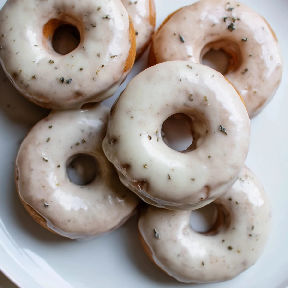 A close-up stack of pillowy Earl Grey mochi donuts showing their signature bouncy texture and crackled white glaze infused with fragrant black tea notes.