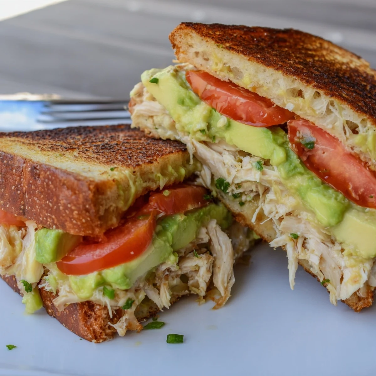 Golden toasted chicken avocado melt sandwich with melted provolone cheese oozing from crispy sourdough bread