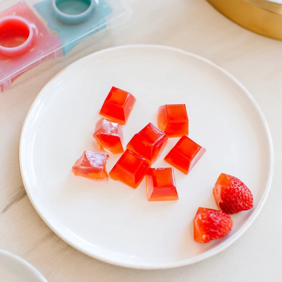 Chewy homemade strawberry gummies arranged on a white plate, showcasing their vibrant red color and heart-shaped molds