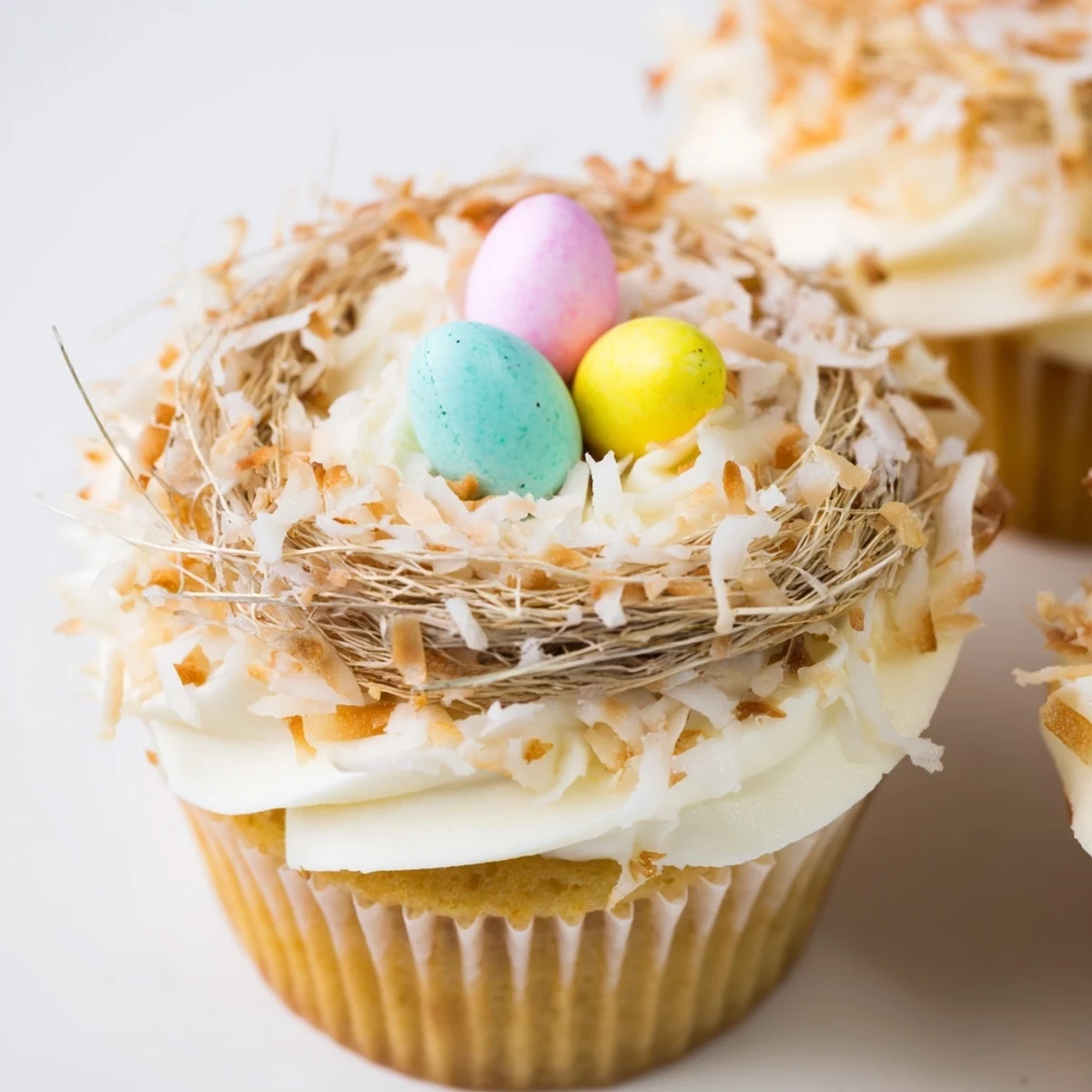 Easter coconut nest cupcakes featuring toasted coconut nests filled with colorful mini chocolate eggs