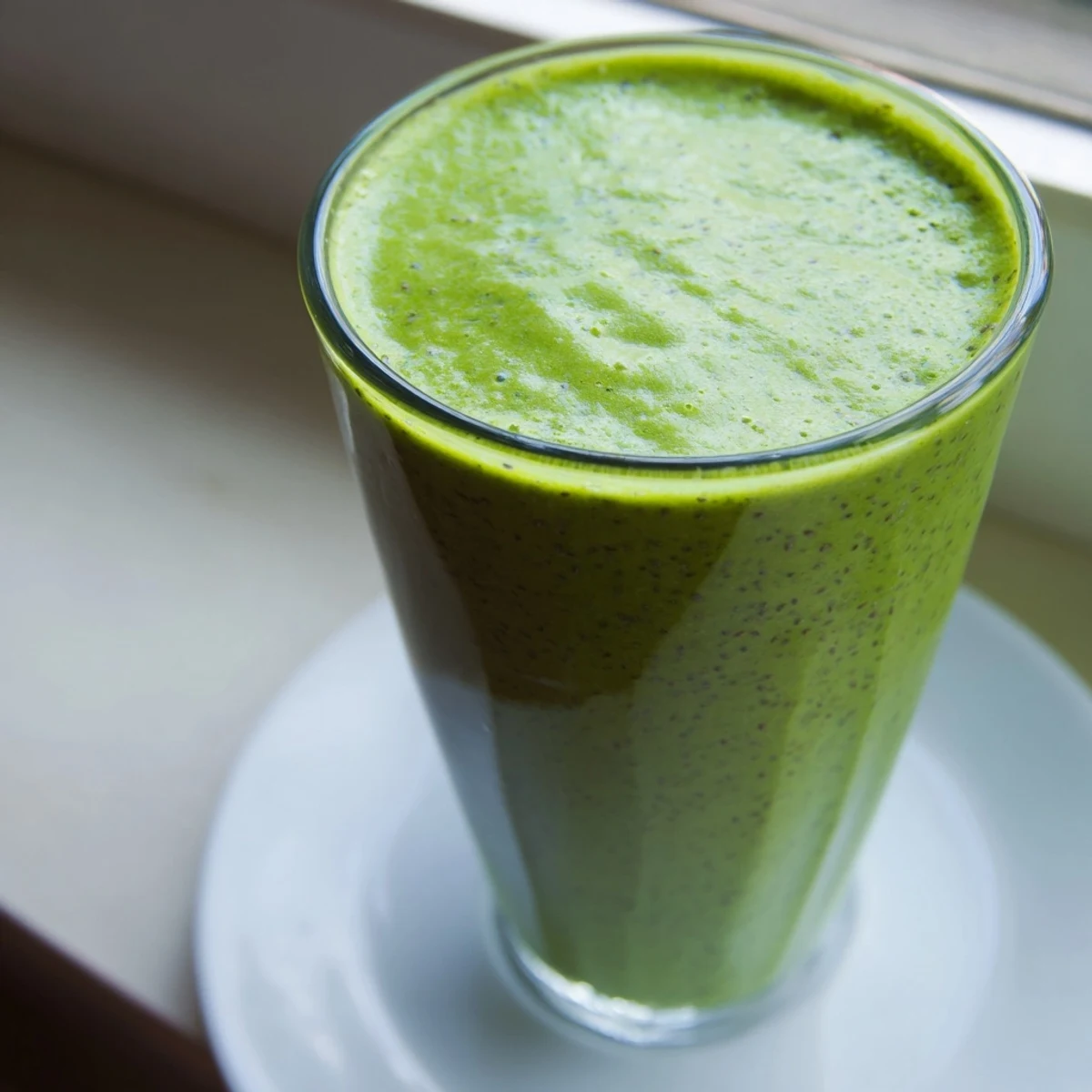 Thick banana matcha smoothie poured into a tall glass topped with ice and optional chia seeds