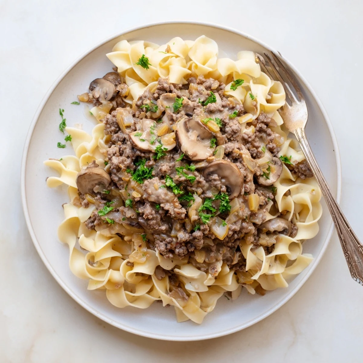 Creamy hamburger stroganoff with ground beef and mushrooms served over tender egg noodles