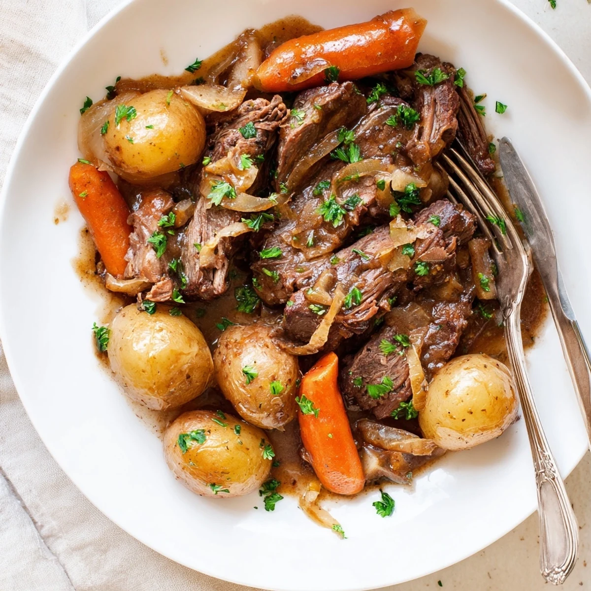 Tender French onion pot roast with caramelized onions, baby potatoes, and rich gravy
