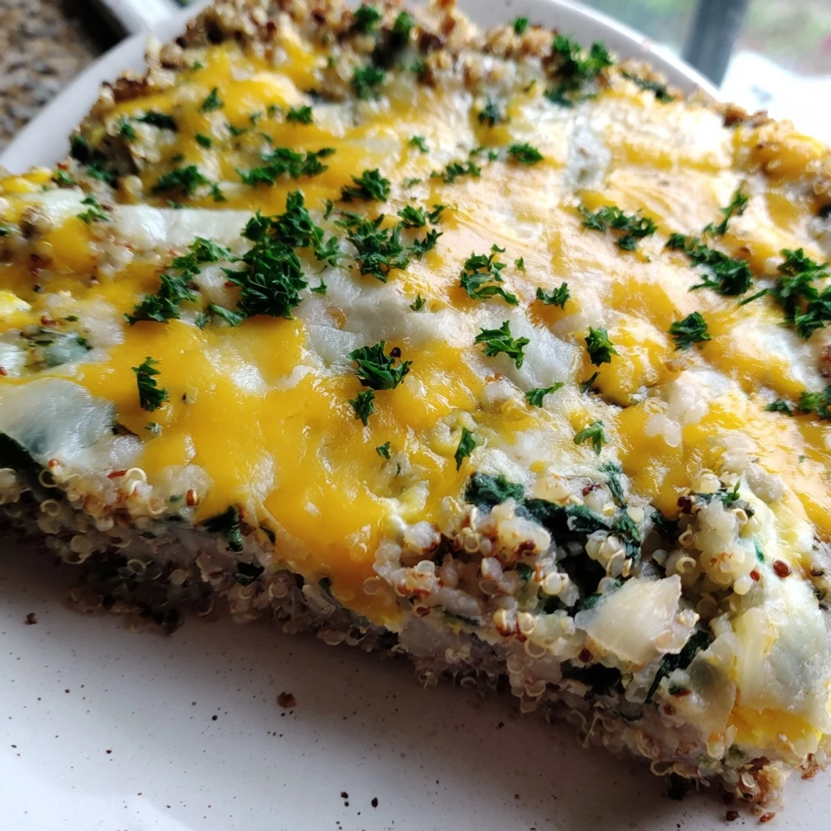 Protein-packed vegetarian quinoa spinach and egg bake featuring a cheesy crust and vibrant green spinach throughout