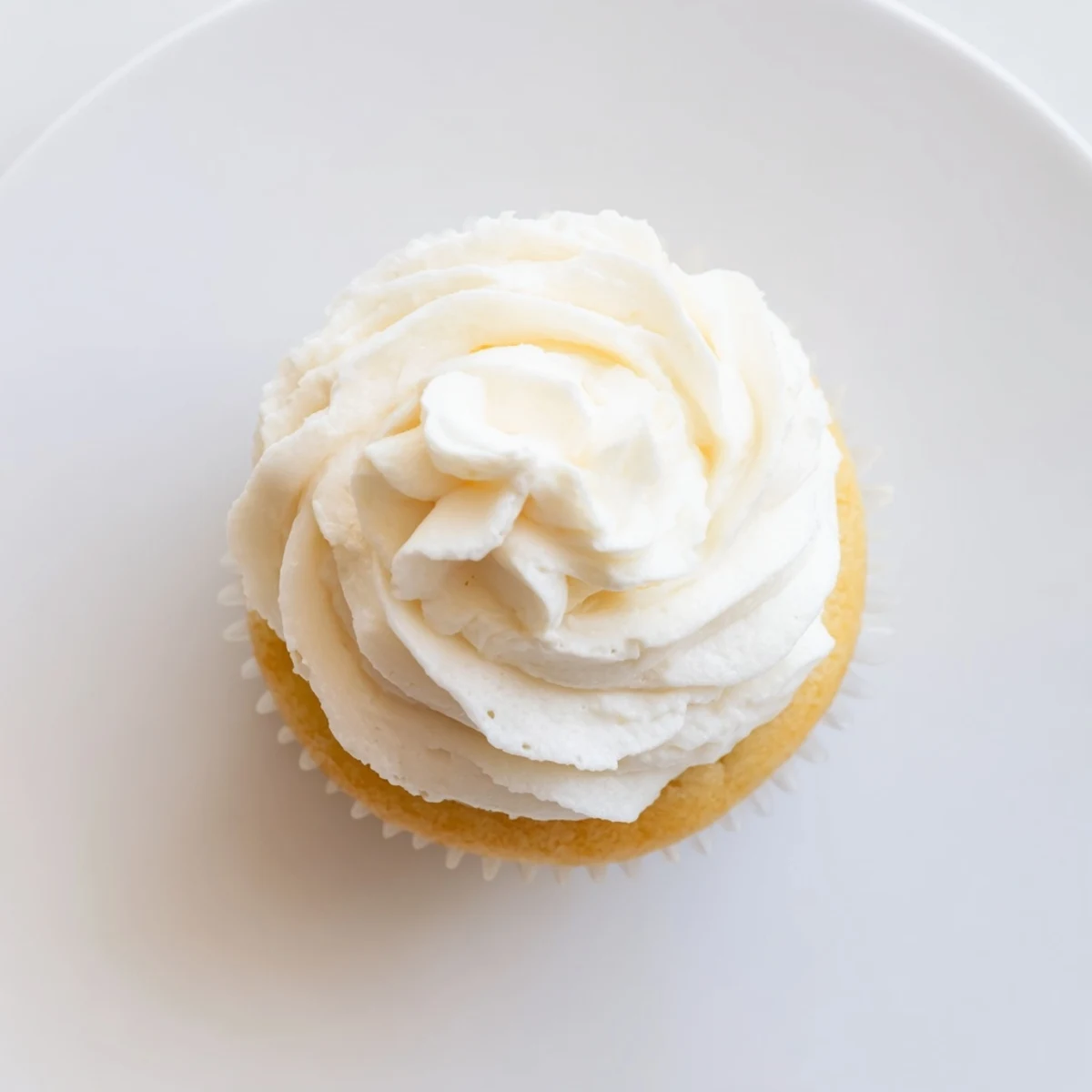 Batch of twelve homemade vanilla cupcakes with domed tops ready for sweet vanilla buttercream frosting