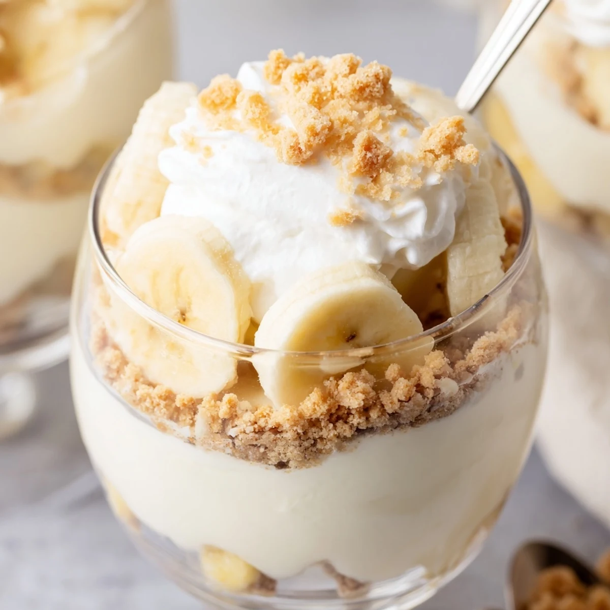 Individual no bake banana pudding cheesecake cups topped with fresh banana slices