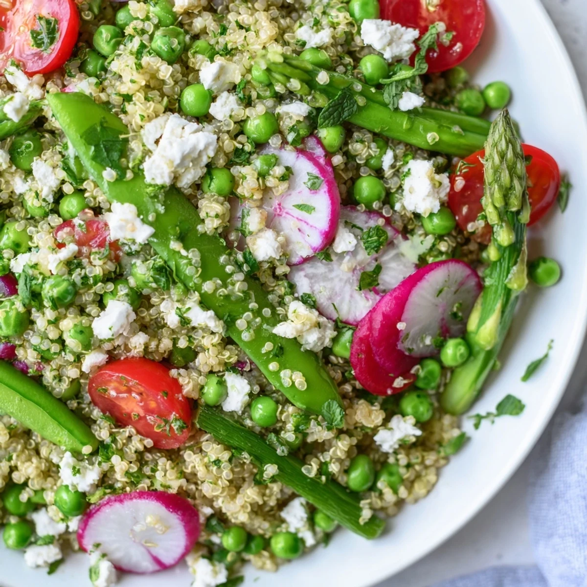Spring vegetable quinoa salad in a white bowl with fresh herbs and lemon vinaigrette