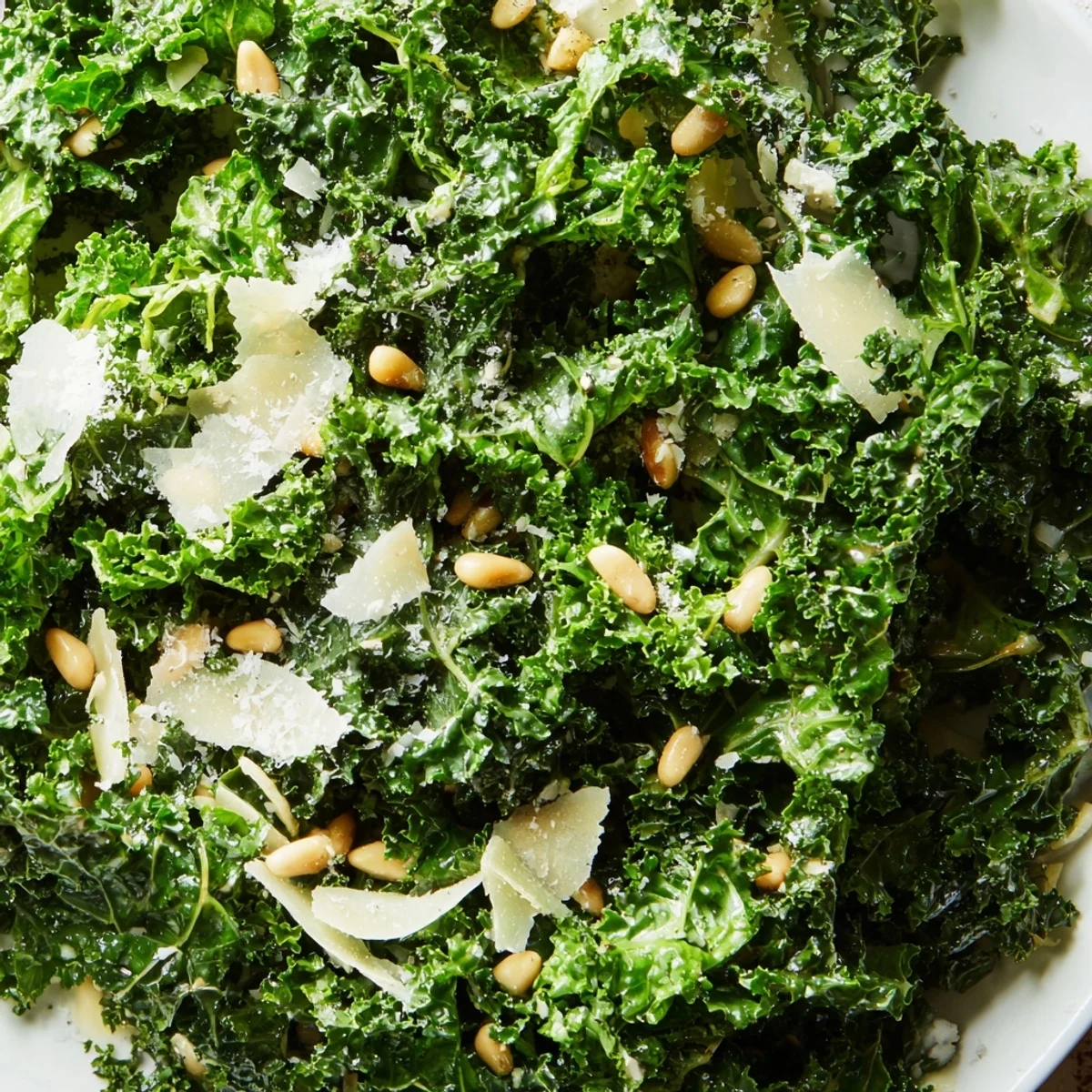 Massaged curly kale glistening with zesty garlic lemon Parmesan dressing in a wooden bowl
