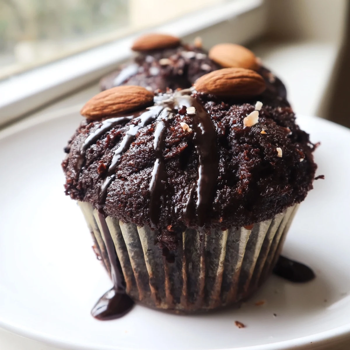 Warm Flourless Almond Joy Cupcakes fresh from the oven, crowned with coconut filling and a luscious chocolate drizzle