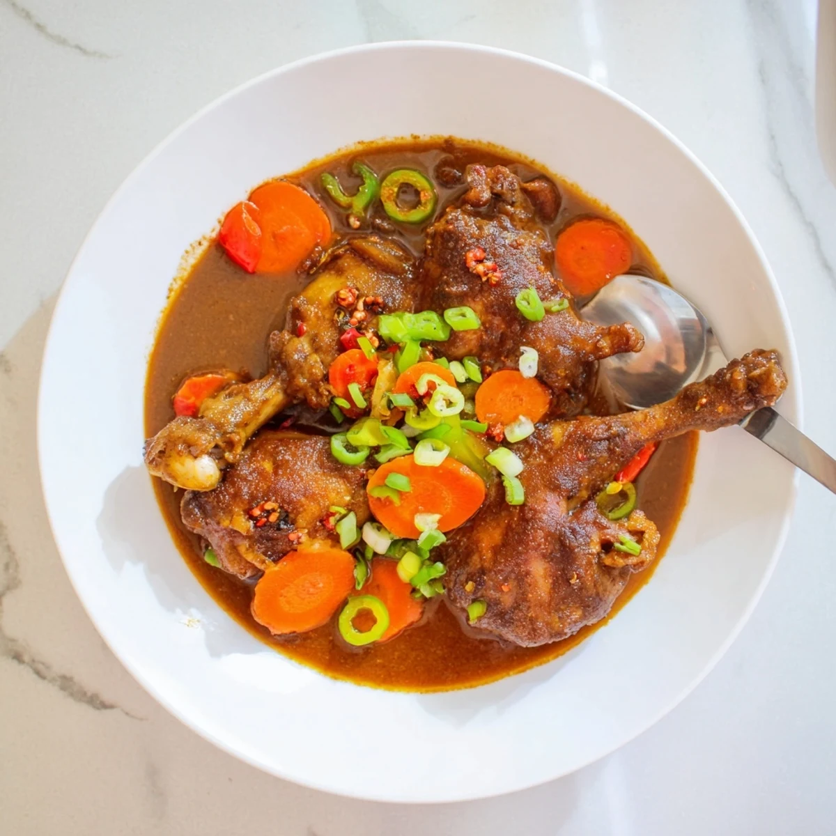 Tender Jamaican brown stew chicken simmered in a rich, spiced gravy with colorful vegetables