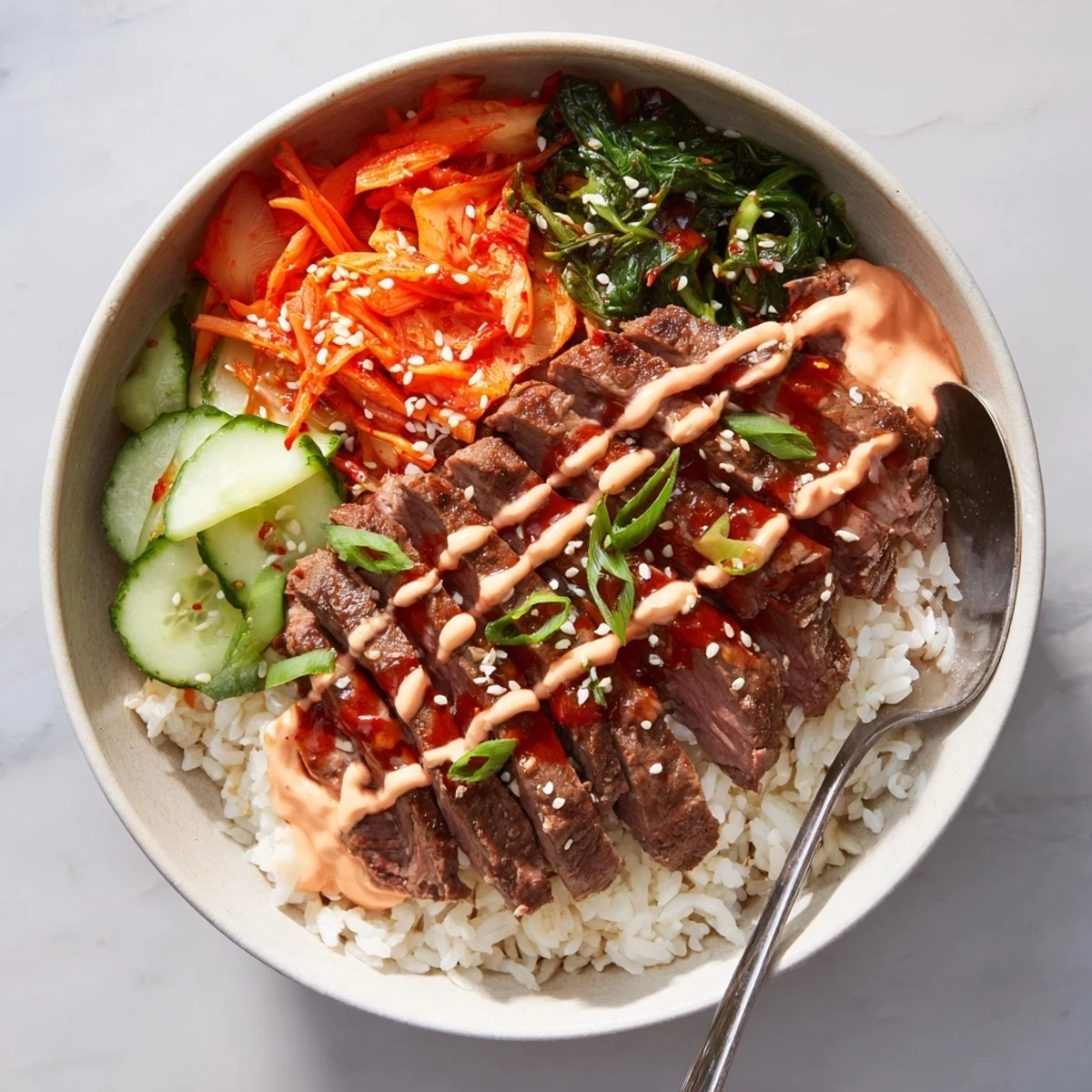 Caramelized marinated steak over fluffy rice topped with drizzled spicy cream sauce in Korean BBQ steak rice bowls