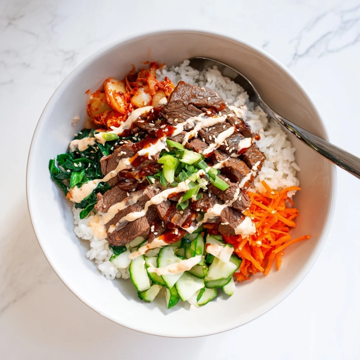 A hearty Korean BBQ steak rice bowl with crisp carrots, kimchi, and a creamy Sriracha drizzle on warm jasmine rice